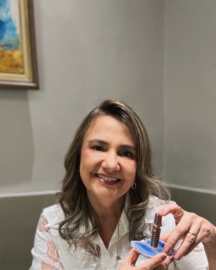 Dra. Virgínia Aragão no consultório com modelo de implante